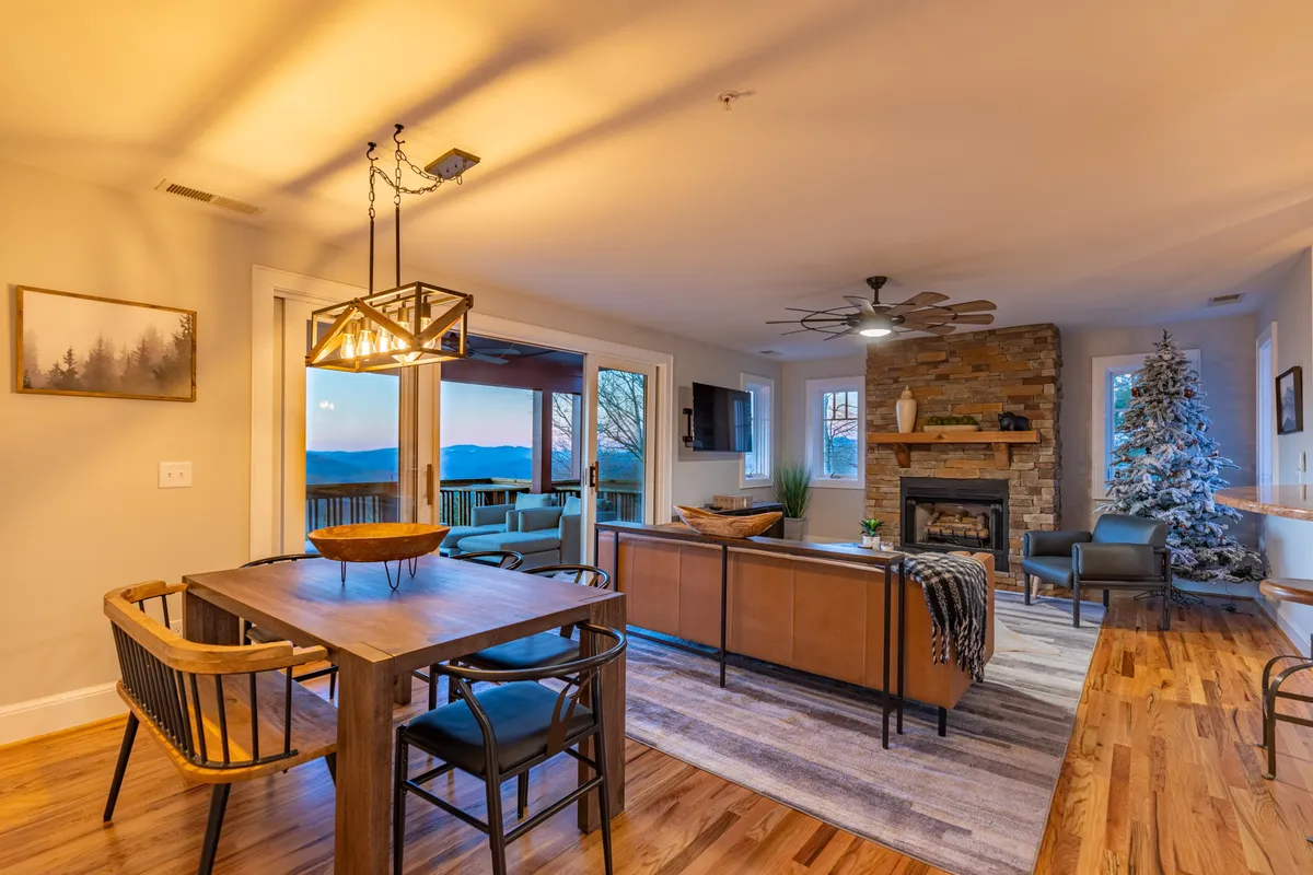 A spacious dining area with a large table, a welcoming fireplace, a decorated Christmas tree, and expansive windows. The scene exudes warmth and is clearly designed for memorable family meals or celebrations.